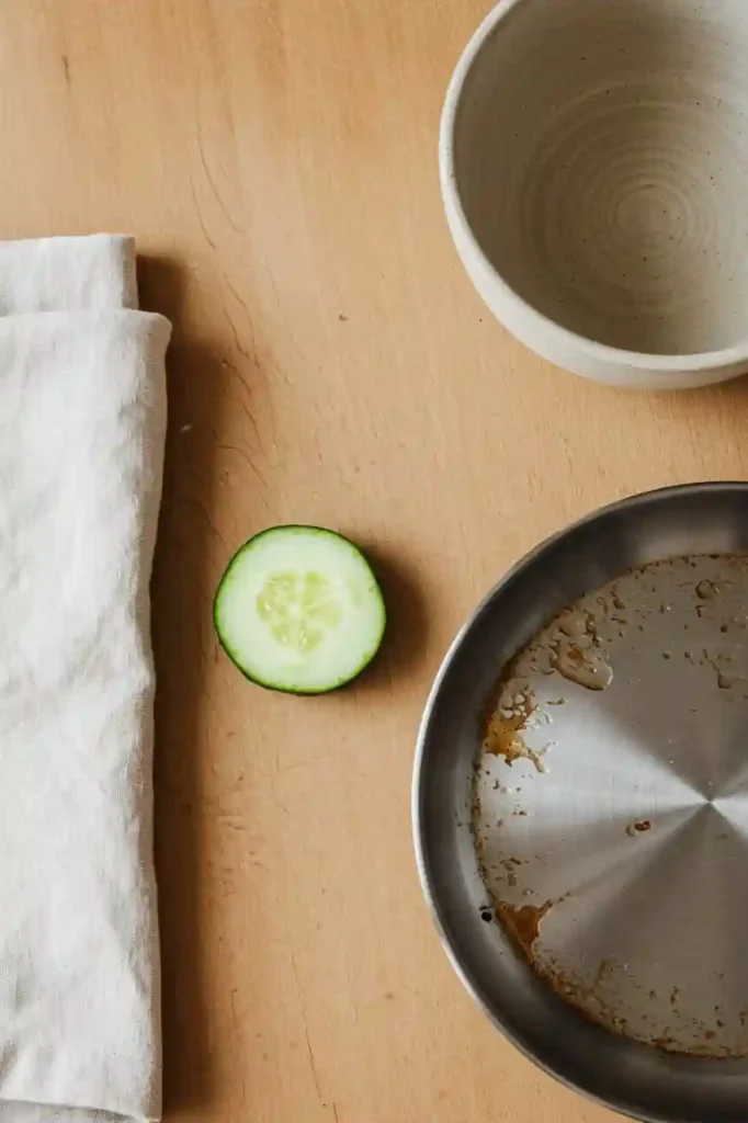 Thick cucumber slice, greasy pan, and paper towel on wooden surface